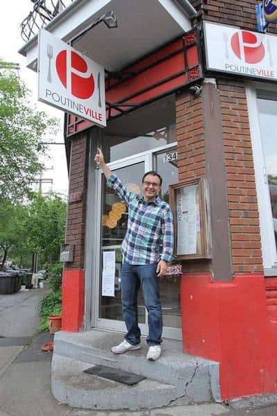 John Catucci de la télésérie You Gotta Eat Here! de Food Network devant la porte d'entrée pointant l'enseigne de Poutineville