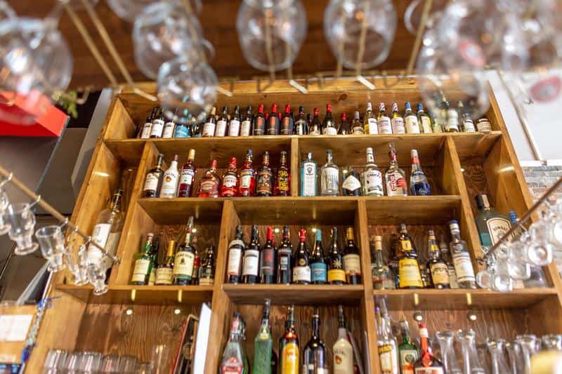 Un présentoir en bois avec plusieurs bouteilles de boissons alcoolisés et bouteille de vin
