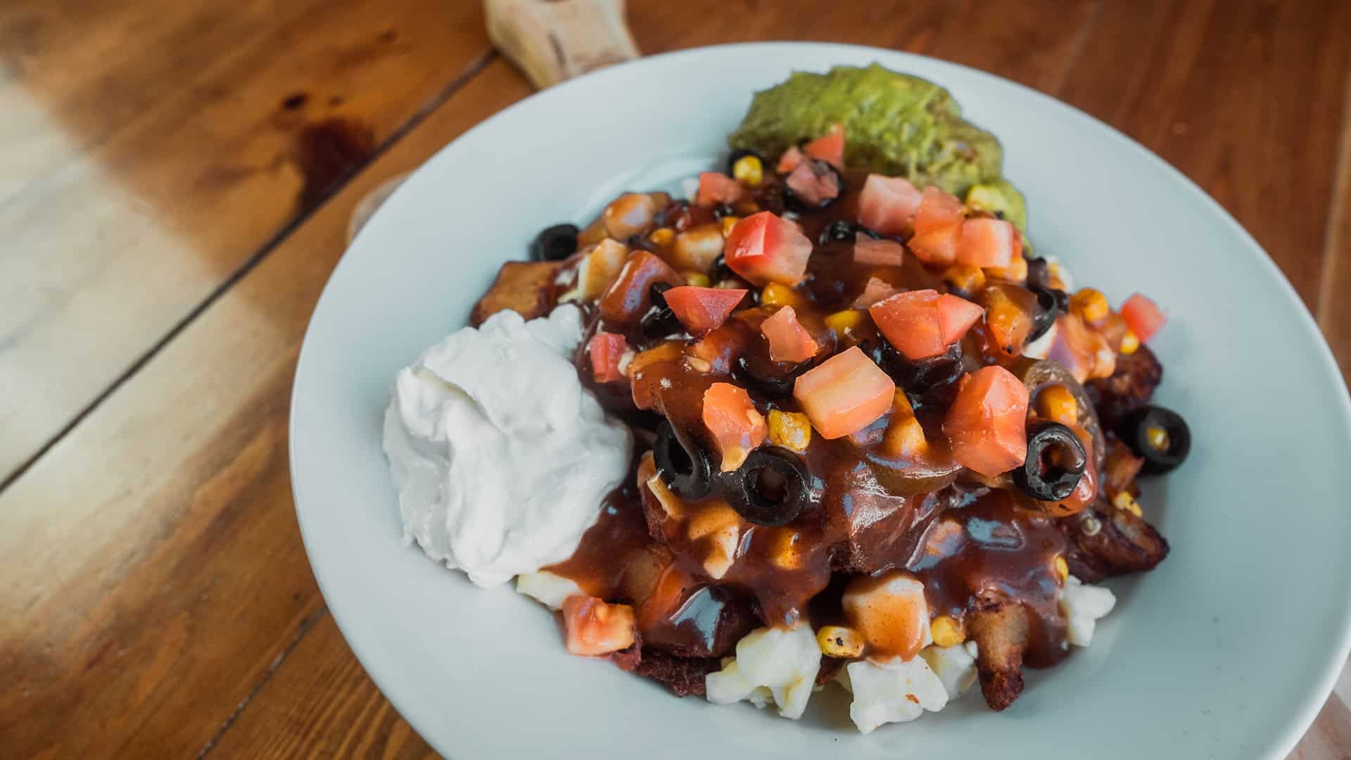 Poutine avec tomate, olive, mais, jalapeno, creme sure et guacamole